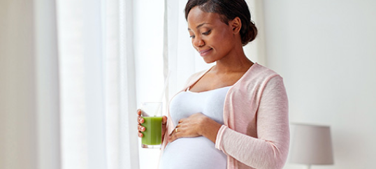 A pregnant woman smiling and touching her belly.